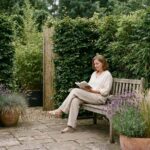Femme assise dans un jardin aménagé avec haies épaisses et panneaux en bambou pour un confort acoustique et visuel optimal