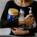 une femme avec des produits d'entretien dans les bras