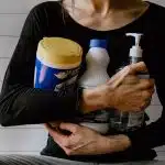 une femme avec des produits d'entretien dans les bras
