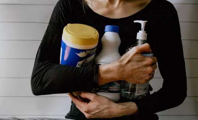 une femme avec des produits d'entretien dans les bras