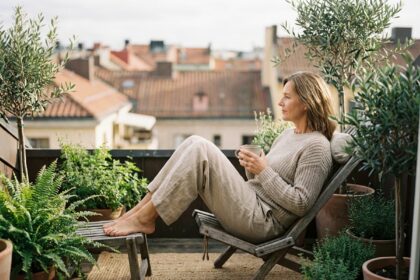 Femme détendue sur balcon urbain avec plantes et thé