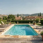 Belle piscine résidentielle extérieure en Haute-Garonne avec terrasse en bois et paysage occitan en arrière-plan
