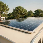 Panneau solaire monocristallin installé sur le toit d'une caravane beige dans un camping entouré de pins