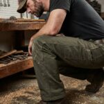 Homme portant un pantalon de travail en toile renforcée dans un atelier de bricolage