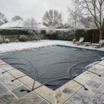 Piscine rectangulaire recouverte d'une bâche d'hivernage sombre en hiver