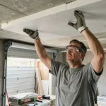Homme posant un panneau isolant rigide au plafond d'un garage lors d'une installation DIY en une journée