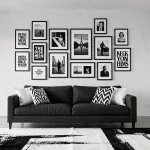 Salon contemporain noir et blanc avec galerie murale de cadres et affiches au-dessus d'un canapé en lin gris anthracite