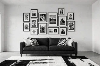 Salon contemporain noir et blanc avec galerie murale de cadres et affiches au-dessus d'un canapé en lin gris anthracite