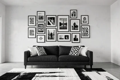 Salon contemporain noir et blanc avec galerie murale de cadres et affiches au-dessus d'un canapé en lin gris anthracite