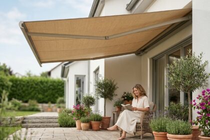 Store banne beige déployé sur une terrasse en bois d'une maison moderne, femme qui lit sous l'ombre protectrice en été