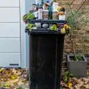 black trash bin with green leaves