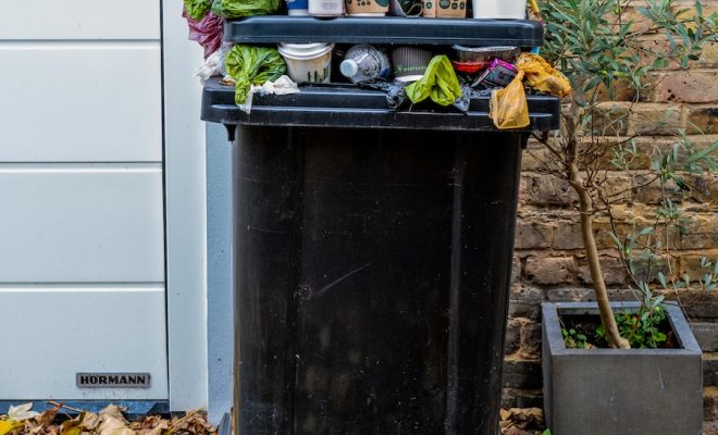 black trash bin with green leaves