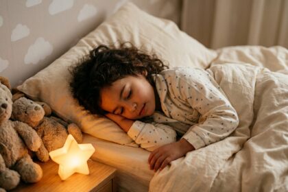 Petite fille endormie dans sa chambre avec une veilleuse apaisante sur la table de nuit